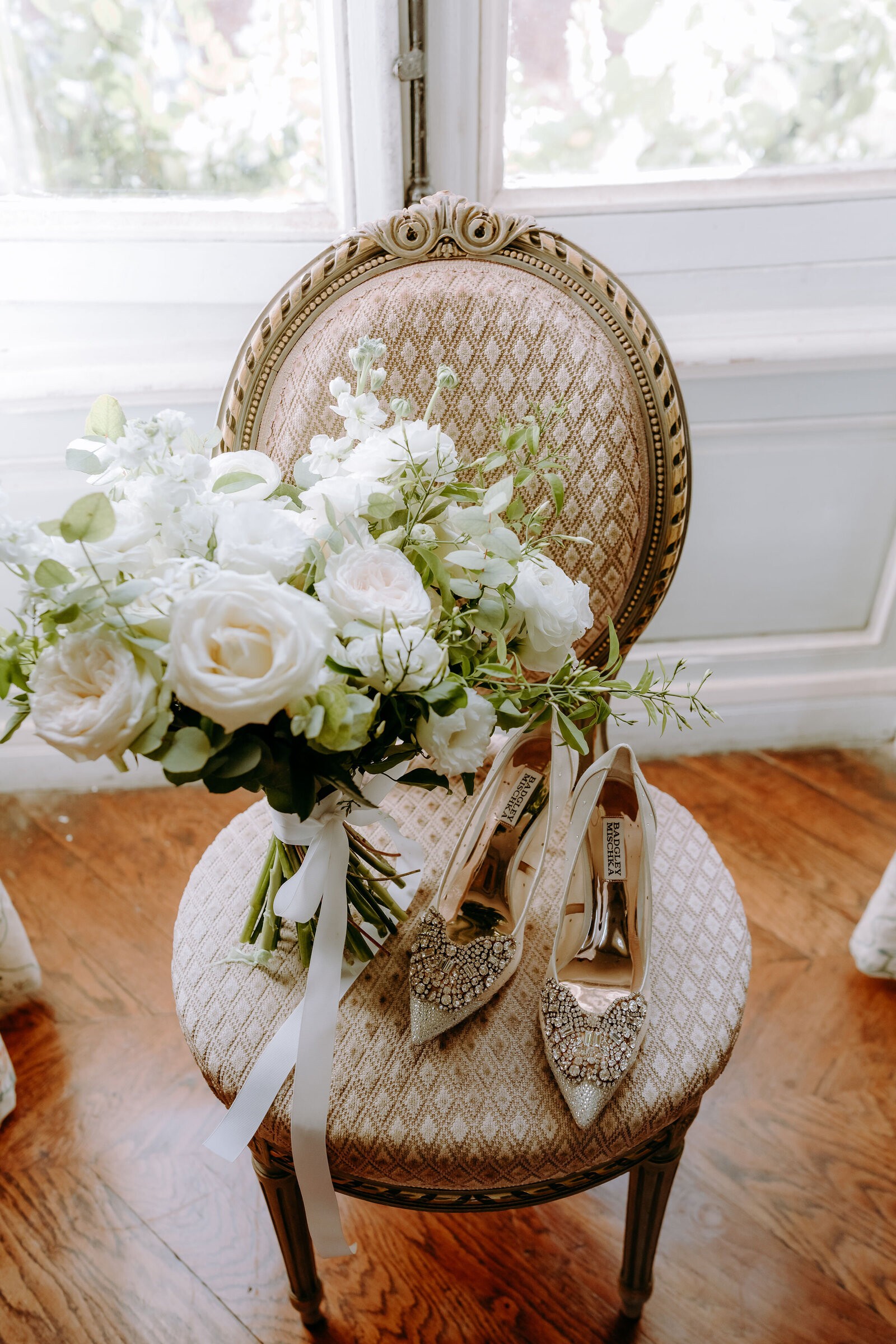 White bridal bouquet and embellished heels on a gilded French chair at Château de Bouthonvilliers