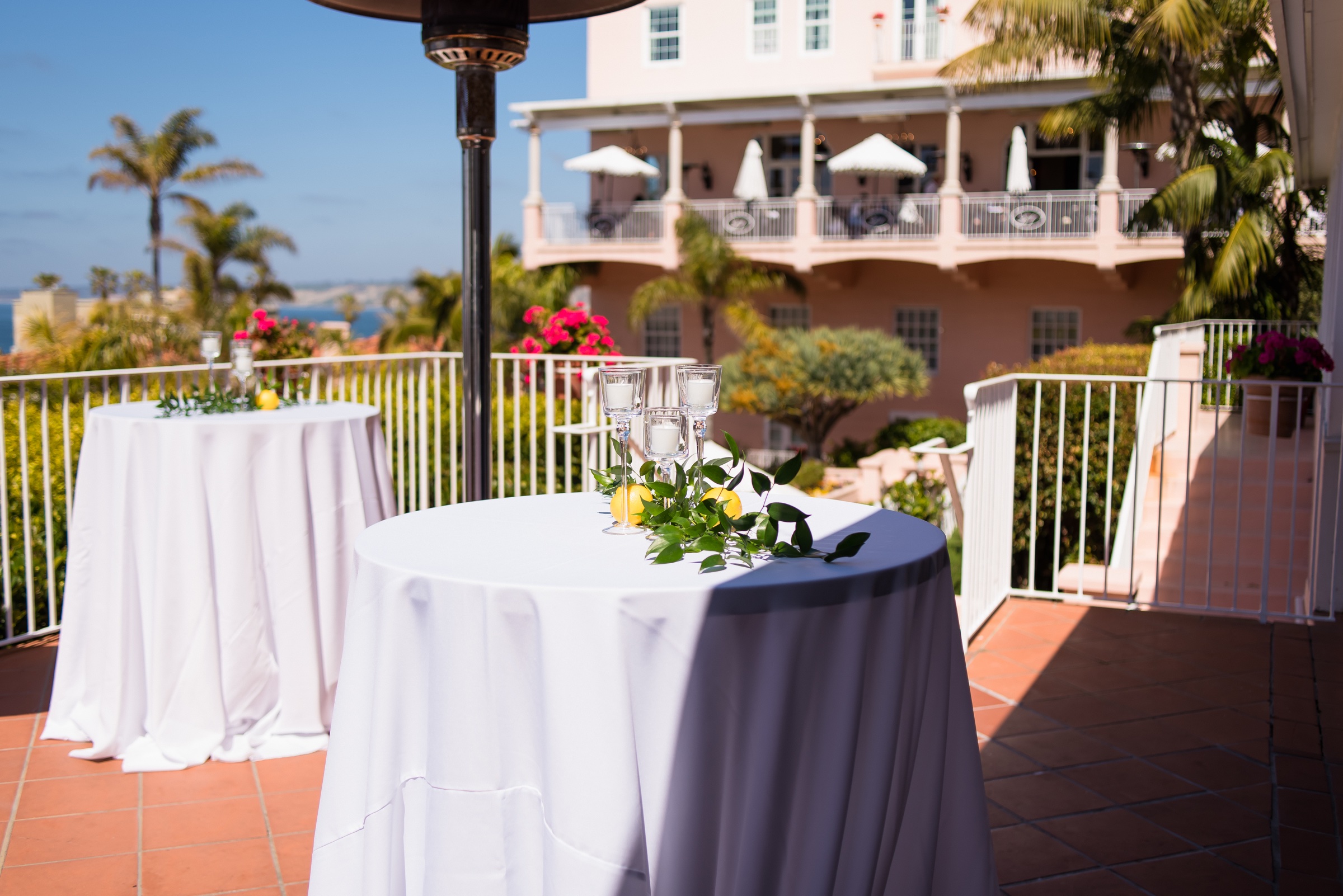 Cocktail tables on the Terraza at La Valencia Hotel with lemons and greenery, pink hotel and ocean behind