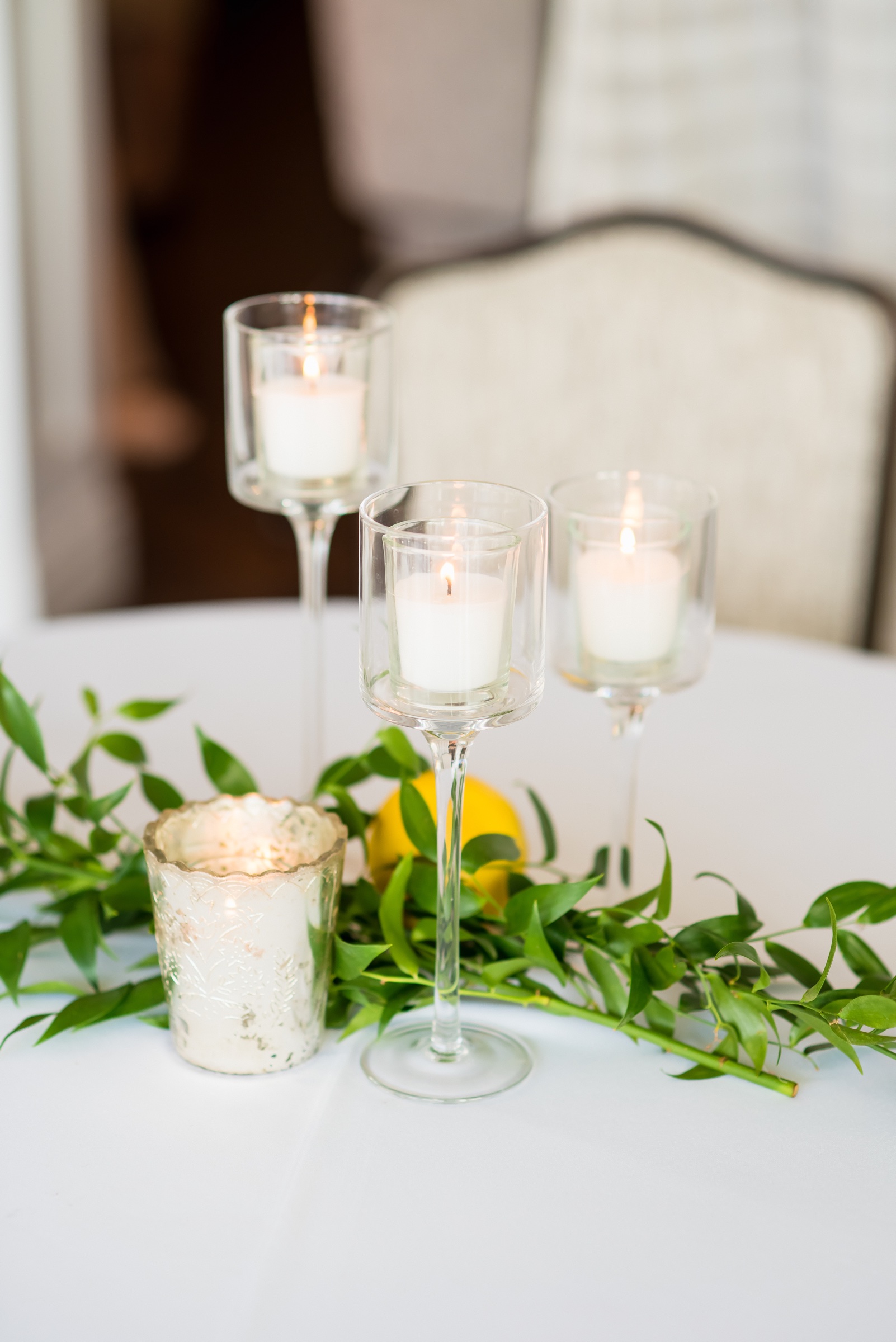Cocktail table with Italian ruscus, a lemon, and stemmed votive candles at La Valencia Hotel