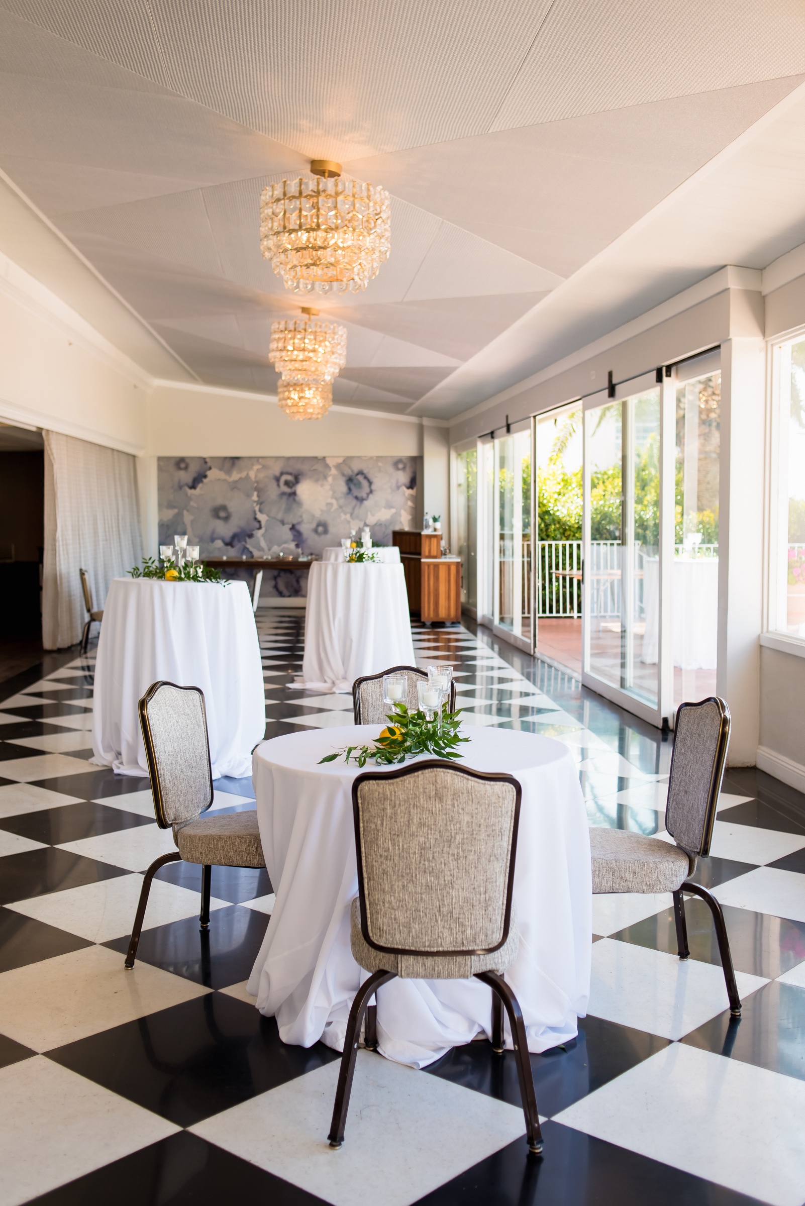 Veranda Ballroom at La Valencia Hotel set with cocktail tables under crystal chandeliers
