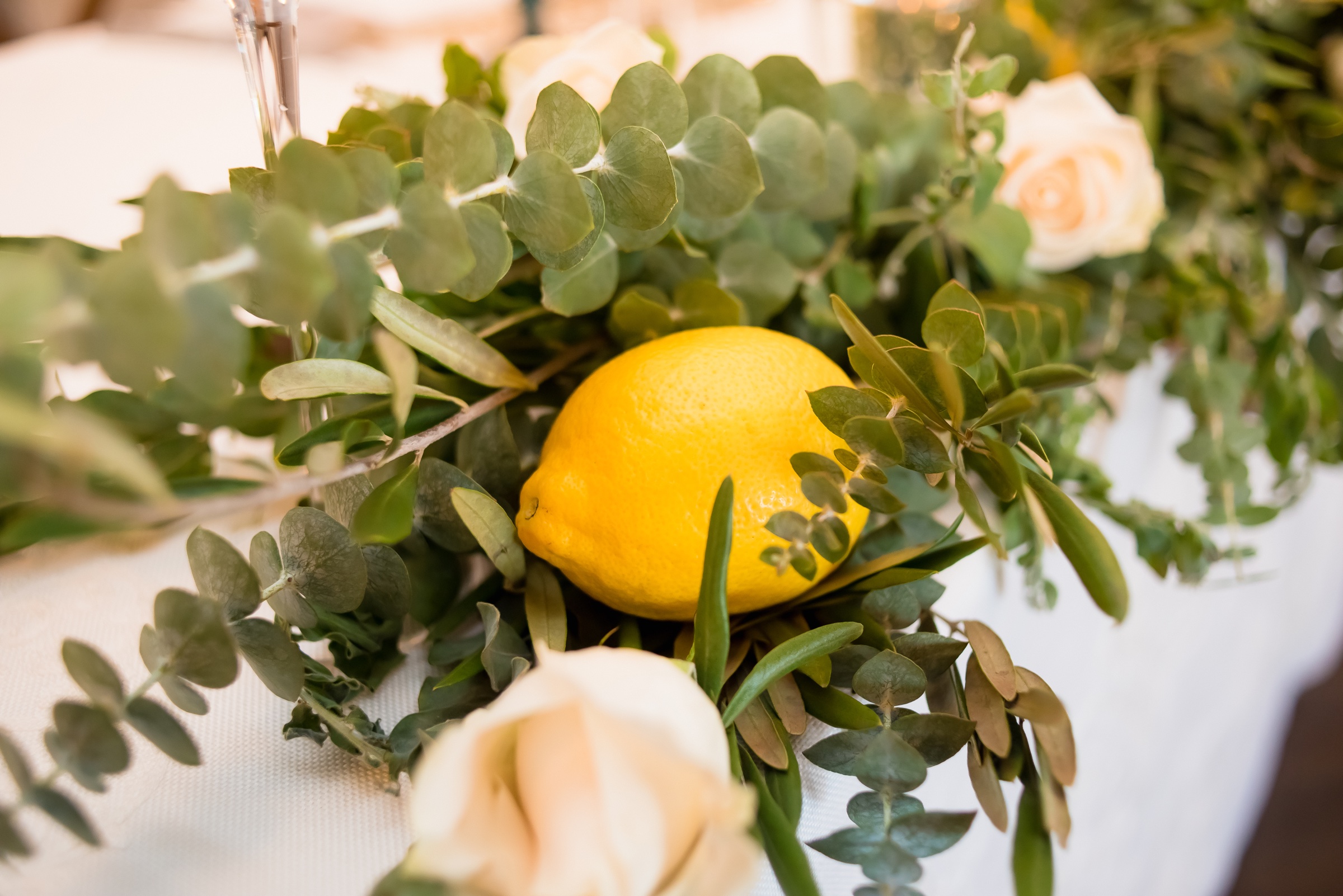 Olive and eucalyptus garland with a lemon and cream roses on a wedding table