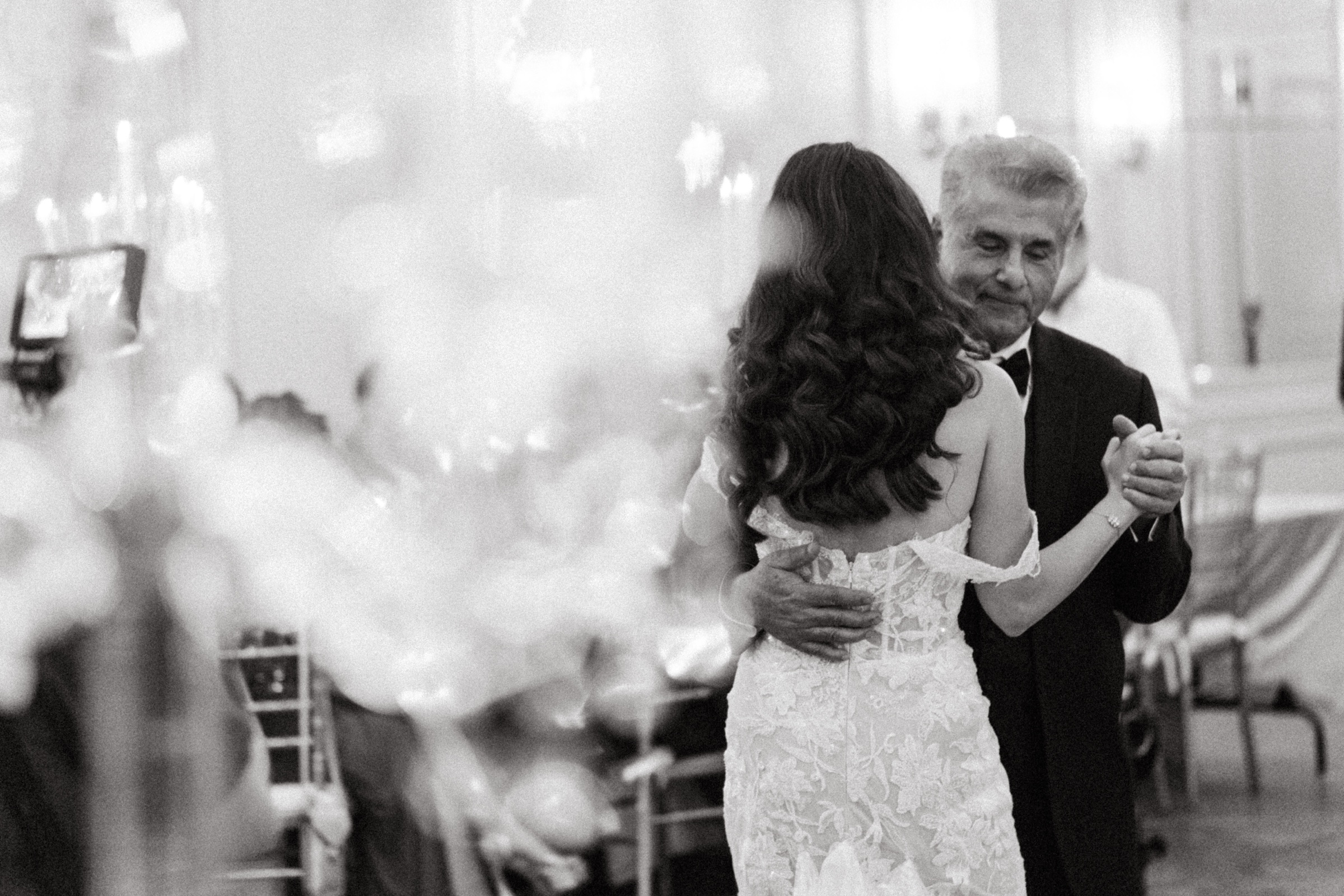 Cherine and Andy dancing under the chandeliers at The Westgate Hotel, in black and white