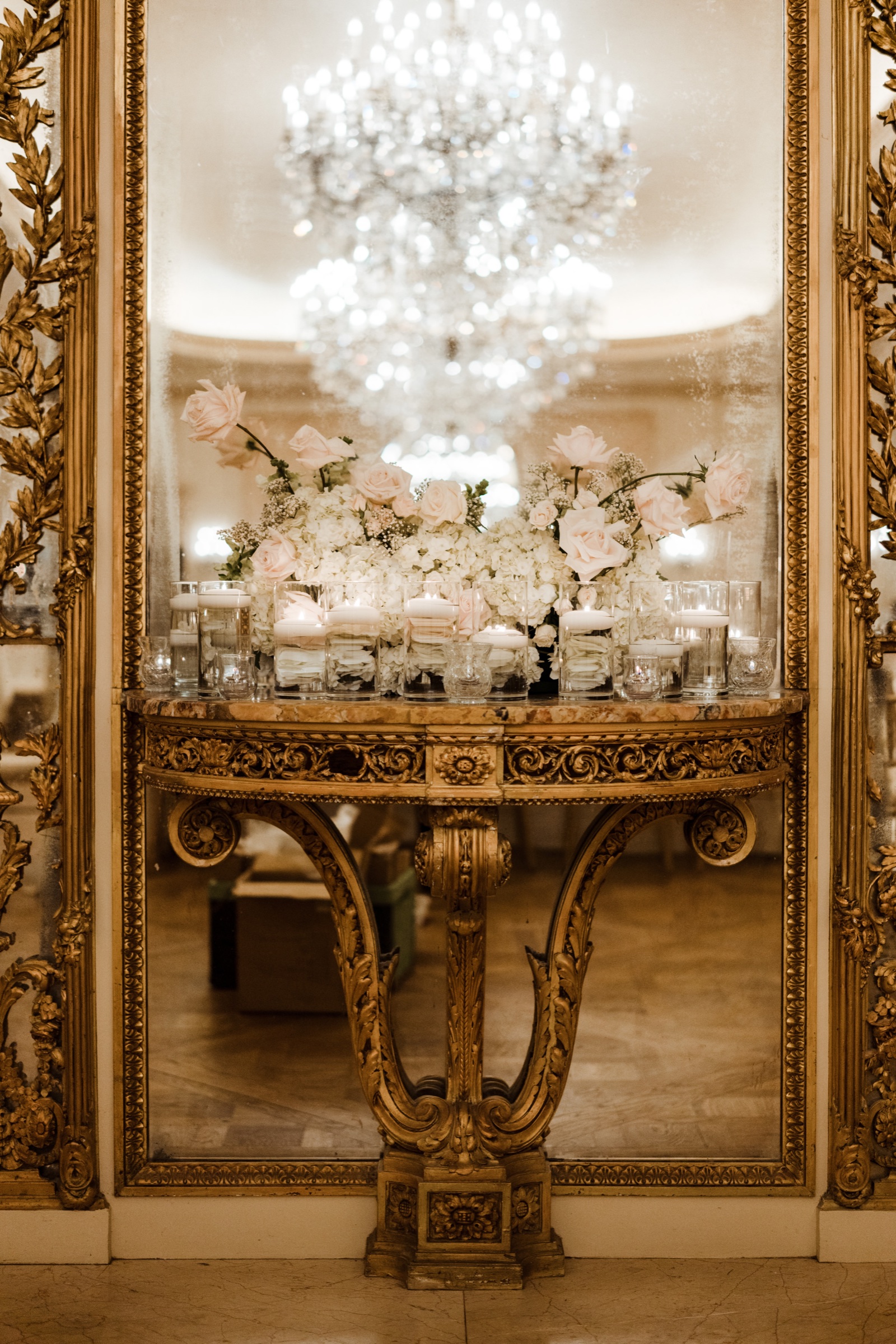Sofreh Aghd framed by a gold mirror and a crystal chandelier with white florals