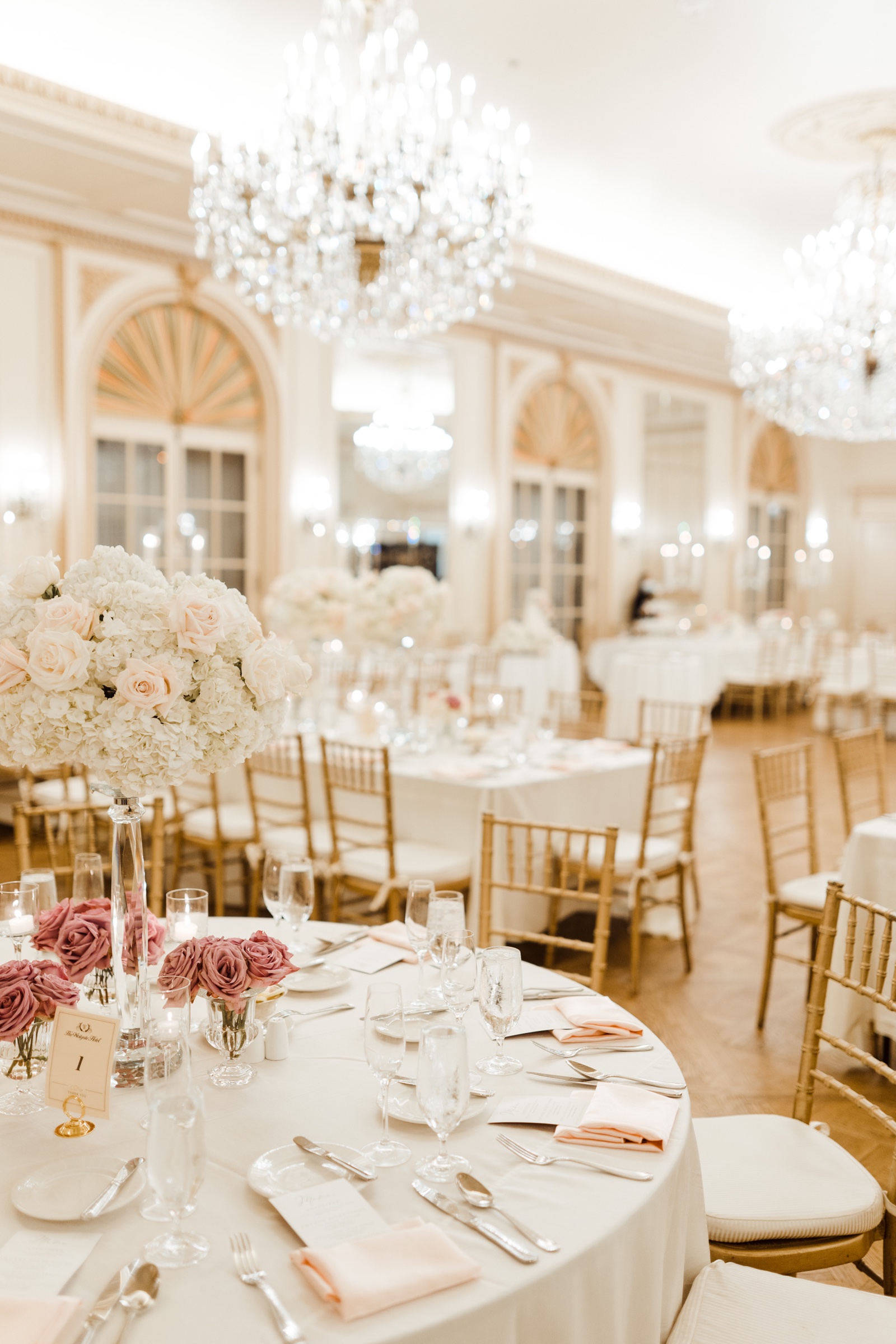 Long reception table with white floral centerpieces and gold chiavari chairs