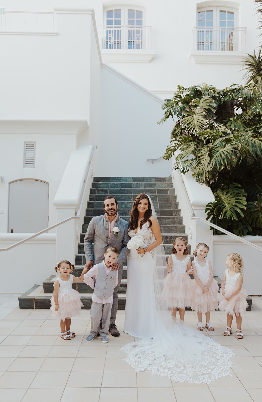 Erica and Patrick with their flower girls and ring bearer on the white courtyard stairs at Park Hyatt Aviara