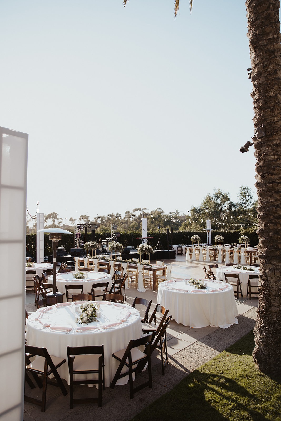 Reception in the Gardens at Park Hyatt Aviara with round tables, string lights, and the band stage under the palms