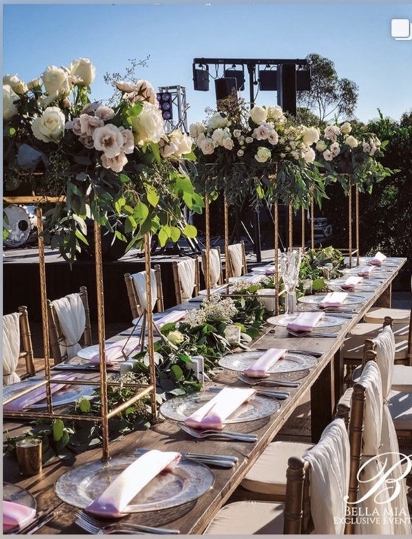 Long reception table with tall white and blush florals, a greenery runner, and the band stage behind at Park Hyatt Aviara in Carlsbad