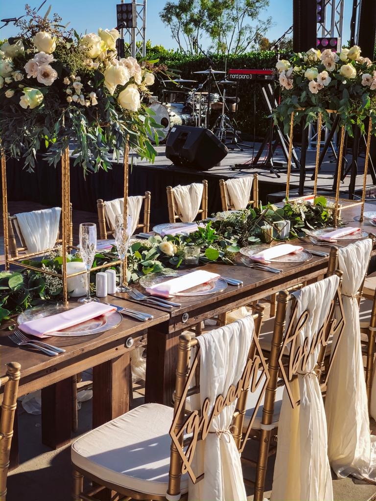 Head table with bride and groom chair signs, gold chiavari chairs, and white and blush florals at Park Hyatt Aviara